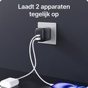 Zwarte 35W snellader met USB-C en USB-A poort, aangesloten op het stopcontact en laadt tegelijkertijd een telefoon en een powerbank op.