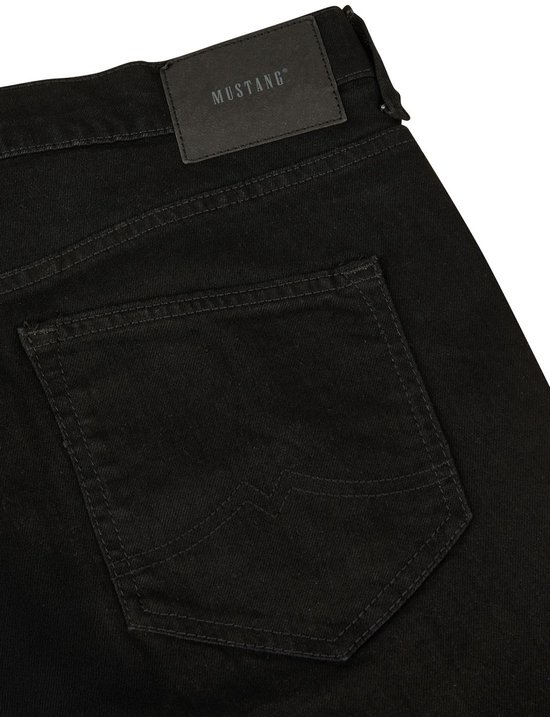 Close-up van de achterkant van een zwarte jeans. De broek heeft een leren Mustang logo met 'True Denim' erop en gestikte achterzakken.