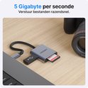 Hub USB-C Voomy 3-en-1 avec ports pour carte SD, micro-SD et USB-A, connecté à un ordinateur portable, à côté d'un objectif d'appareil photo.