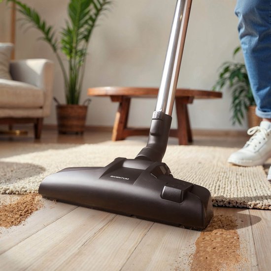 Zuigmond van een stofzuiger die vuil opzuigt van een houten vloer.