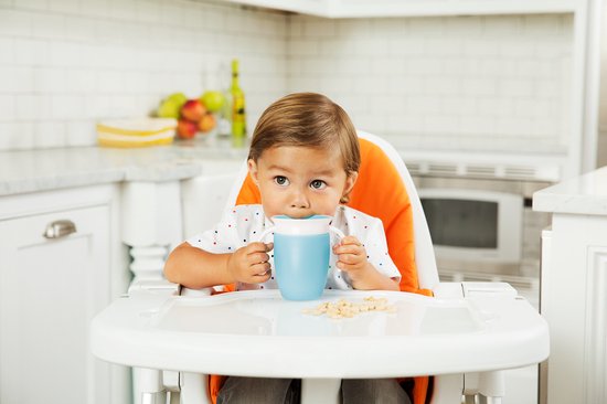 Een jongen in een kinderstoel drinkt uit een blauwe Munchkin Miracle 360° beker.