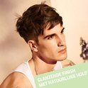 Man met warrig donkerbruin haar met een glanzende finish, gedragen met een natuurlijke hold.