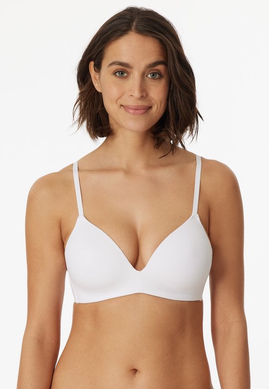 Voorkant van een witte, beugelvrije BH met voorgevormde cups, gedragen door een lachend model.