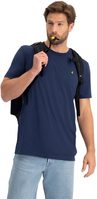 Man met donkerblauwe t-shirt en spijkerbroek, met zwarte rugzak over de schouder en een gele fluit in de mond.
