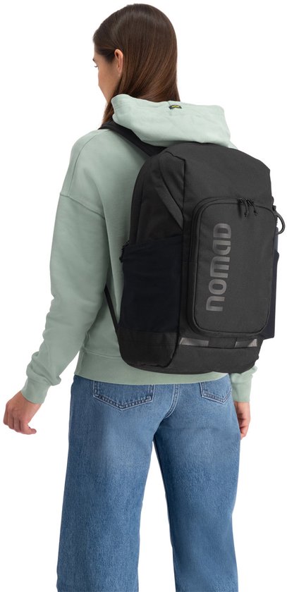 Vrouw met lichtgroene hoodie, draagt een zwarte rugzak, zicht van achteren.
