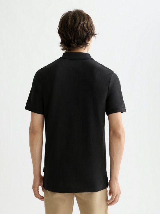 Achterkant van een man in een zwarte poloshirt met korte mouwen.