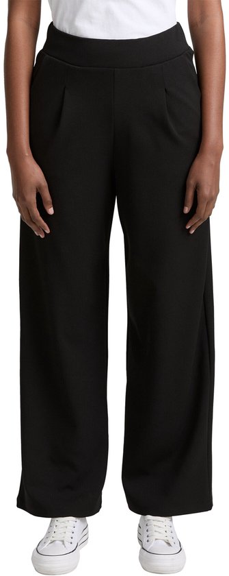 Zwarte wijde broek met witte sneakers.