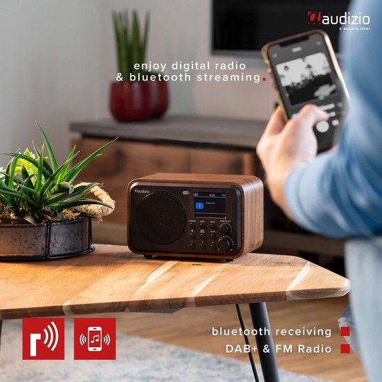 DAB radio met houtlook op een houten tafel, met een smartphone ernaast.