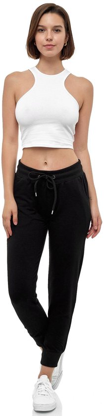 Model in een witte crop top en zwarte joggingbroek met trekkoord en elastische enkelband.
