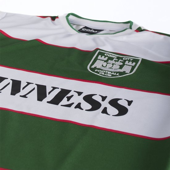 Detail van wit voetbalshirt met groene en witte strepen, rode bies en 'Guinness' opdruk.