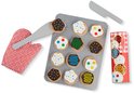 Houten koekjes op bakplaat met rode ovenwant, spatels en rol koekjesdeeg. Koekjes met sprinkles, chocolade, groene en blauwe icing, polka dots.