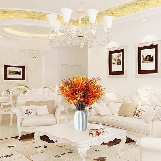 Un bouquet de plantes artificielles oranges, jaunes et brunes dans un vase bleu clair, au milieu d'un salon luxueux.