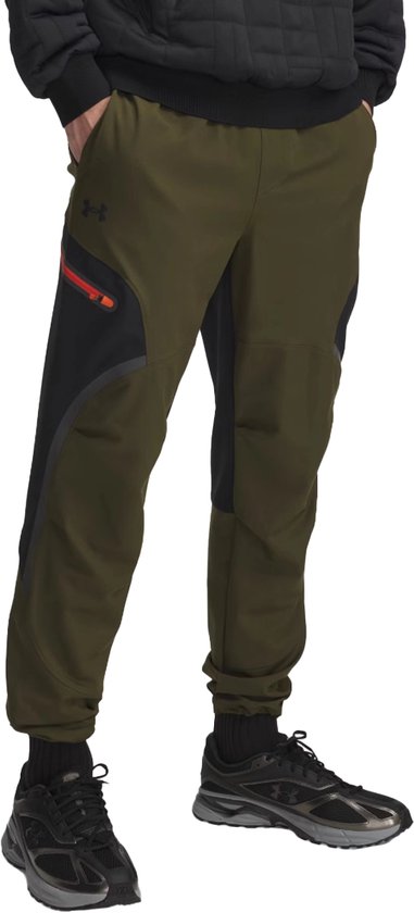 Olijfgroene Under Armour cargobroek met zwarte panelen en oranje ritsaccenten bij de zakken.