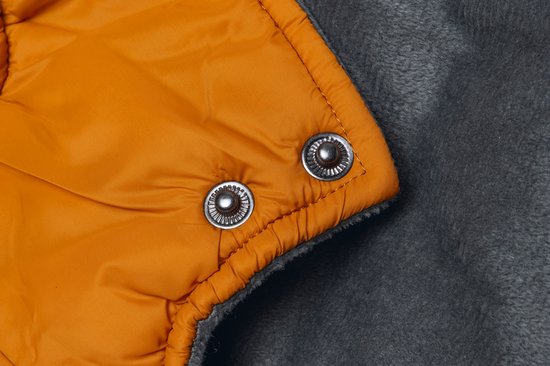 Sluiting van oranje en grijze hondenjas met drukknoopjes.