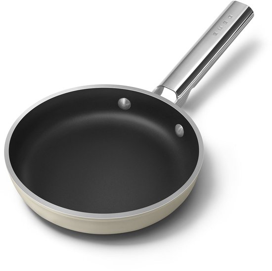 Crème koekenpan met zwarte binnenkant en RVS handvat. De pan is schuin van voren gefotografeerd.