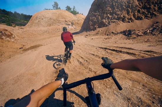 Fietser op een mountainbike in een woestijnlandschap, gefilmd vanuit het perspectief van de persoon erachter.