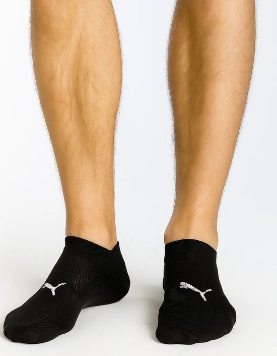 Zwarte enkelsokken gedragen door een man, met een wit Puma logo.