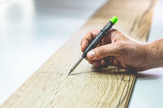 Hand met Pica-Dry markeerstift die een lijn tekent op een houten plank.
