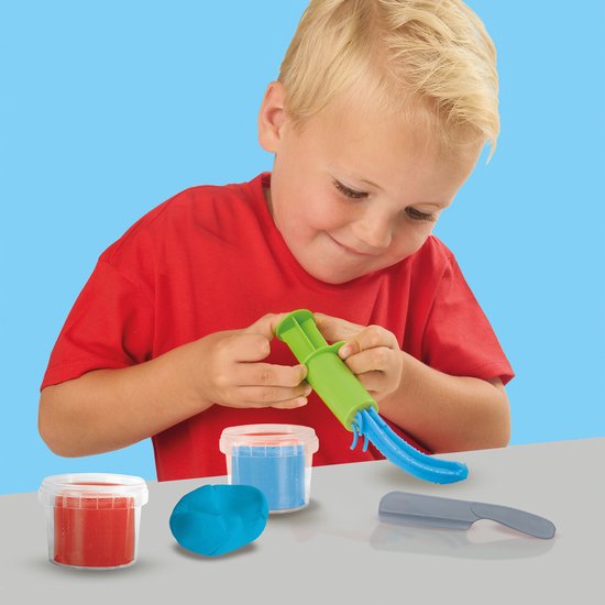 Jongen met blond haar in rode T-shirt speelt met groene kleispuit en blauwe klei.