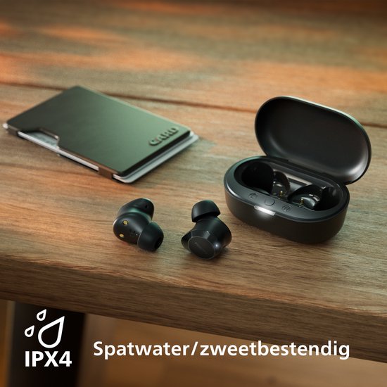 Zwarte oordopjes en open oplaadcase op een houten tafel, met "IPX4 spatwater/zweetbestendig" icoon.