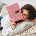 Vrouw met blauwe ogen die een roze dagboek met cijferslot vasthoudt.