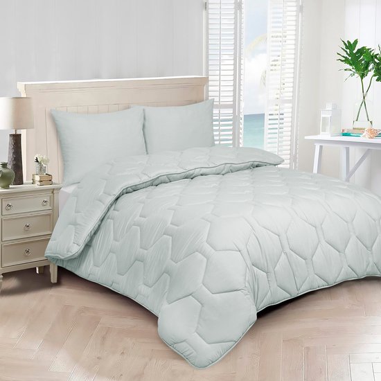 Couette 2-en-1 gris clair avec surpiqûre hexagonale, mise sur un lit avec des oreillers.