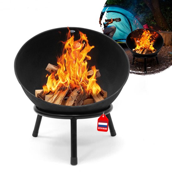Een zwarte stalen vuurkorf met brandend hout, op drie poten. Een tent en een persoon met gitaar in de achtergrond. "Dutch Brand".