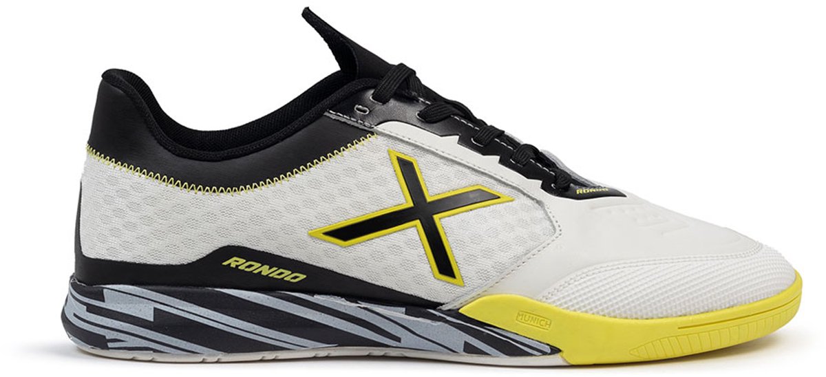 Futuristische witte indoor voetbalschoenen met zwarte en gele accenten, zachte PU bovenkant en gestructureerde teen.