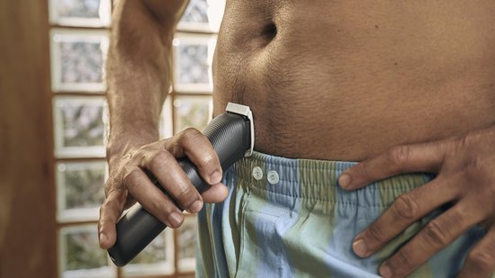 Man gebruikt zwarte Philips trimmer in de intieme zone.