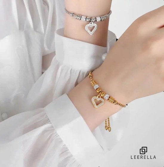 Twee modellen die gouden en zilverkleurige armbanden met hartvormige hangers met zirkonia dragen.