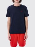 Model draagt een donkerblauw Polo Ralph Lauren T-shirt en rode korte broek.