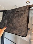 Main tenant une lingette microfibre gris foncé dans une cabine de douche.