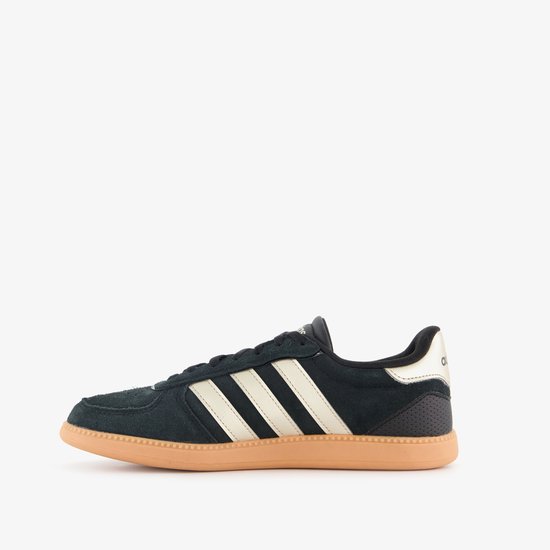 Zijaanzicht van zwarte Adidas sneaker met beige zool, witte strepen en gouden hiel.