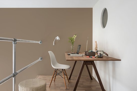 Thuiswerkplek met een houten bureau, witte stoel en een bruine muur.