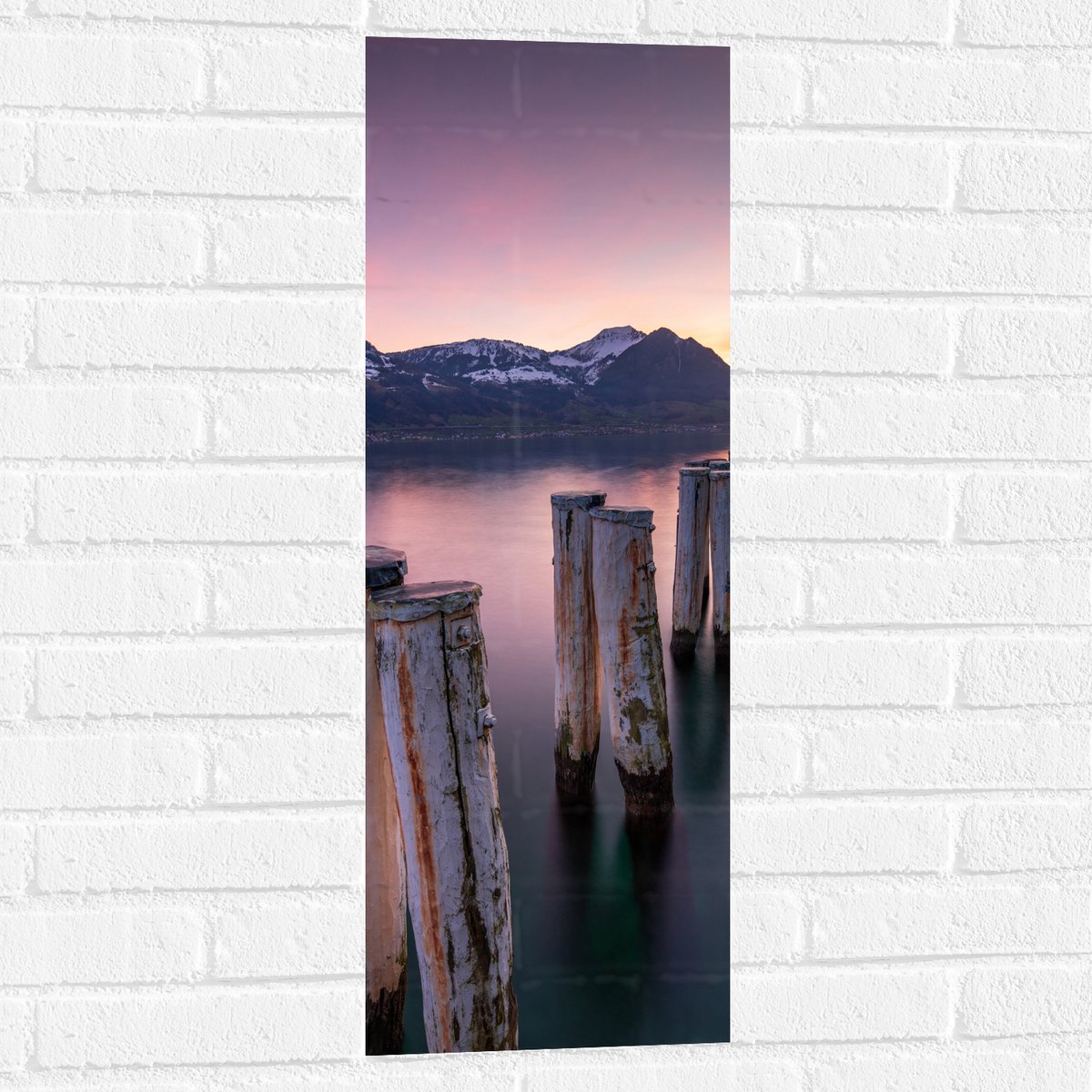 Muursticker - Houten Palen in het Meer van Berggebied tijdens Zonsondergang met Paarse Glo