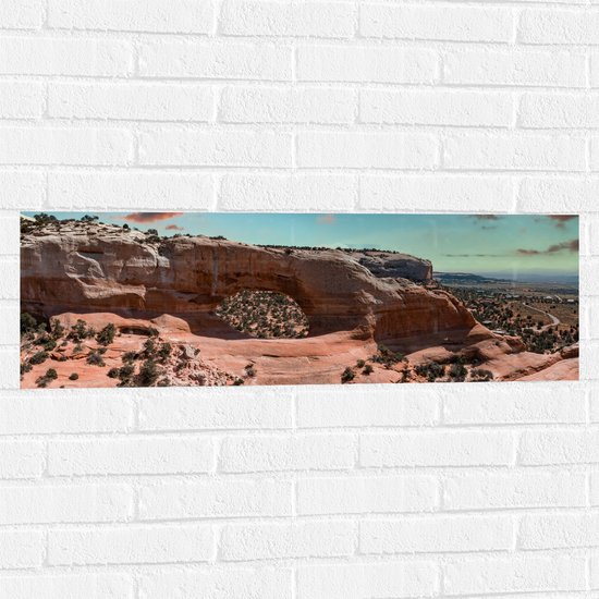 WallClassics - Muursticker - Uitzicht vanaf Rots over Wolken en Rotsen in het Arches National Park in Utah, Amerika - 90x30 cm Foto op Muursticker