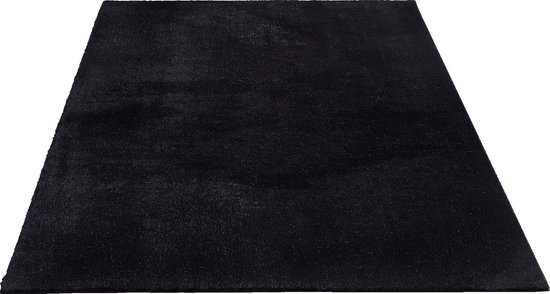 Un tapis noir et doux, vu de face, posé sur un fond noir.