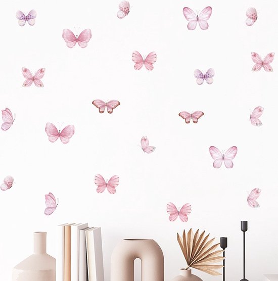 Zachtroze aquarel vlinder muurstickers op een witte muur boven een boekenplank met een vaas en een decoratieve waaier.