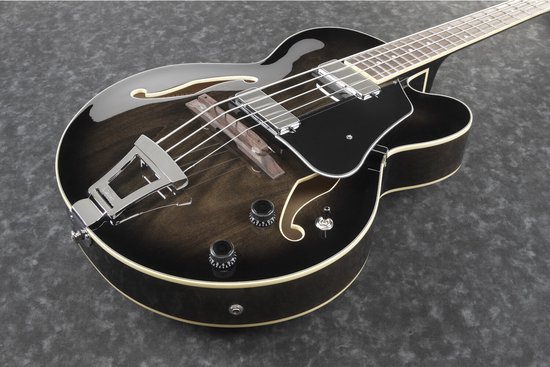 Close-up van de zwarte semi-akoestische Ibanez basgitaar met houtnerfdetails op de body, zwarte slagplaat en zilveren hardware.