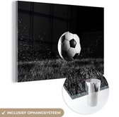 MuchoWow® Glasschilderij 90x60 cm - Schilderij acrylglas - Voetbal in het gras - zwart wit - Foto op glas - Schilderijen