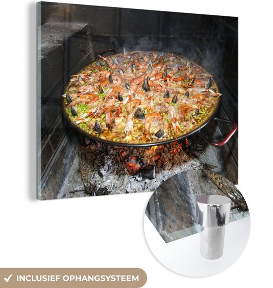 MuchoWow® Glasschilderij 80x60 cm - Schilderij acrylglas - Zeevruchtenrijst gekookt in een brandhou. Paella is een van de traditionele gerechten van Spanje - Foto op glas - Schilderijen