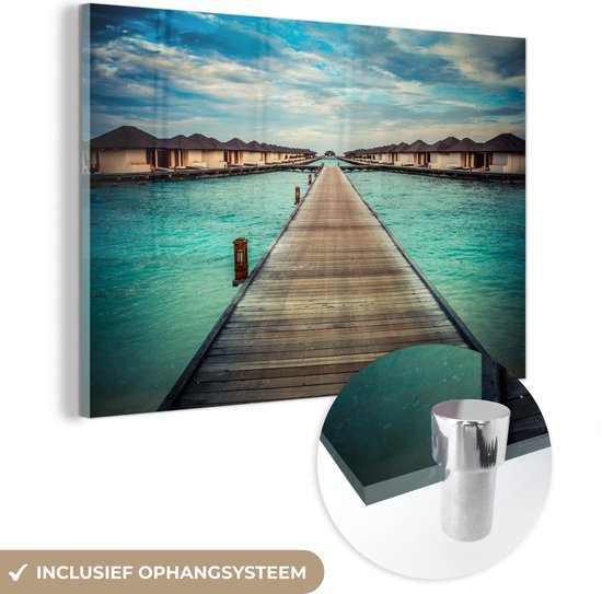 MuchoWow® Glasschilderij 150x100 cm - Schilderij acrylglas - Bungalows met een loopbrug aan het water - Foto op glas - Schilderijen