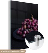 MuchoWow® Glasschilderij 30x40 cm - Schilderij acrylglas - Mysterieuze rode druiven op een donkere tafel - Foto op glas - Schilderijen