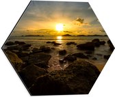 Dibond Hexagon - Zon verdwijnend achter Wolken boven de Zee vol Rotsen - 40x34.8 cm Foto op Hexagon (Met Ophangsysteem)