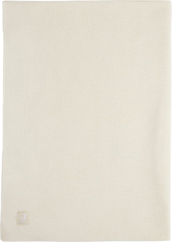 Couverture bébé en maille crème avec une petite étiquette en bas à droite.