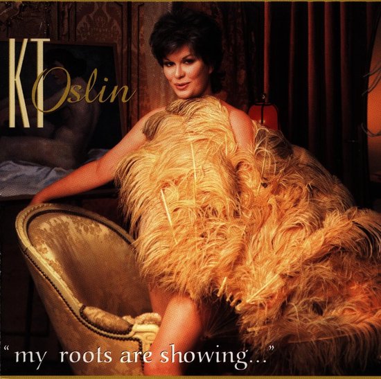 KT Oslin met grote oranje veren in een fauteuil. Titel: "my roots are showing..."