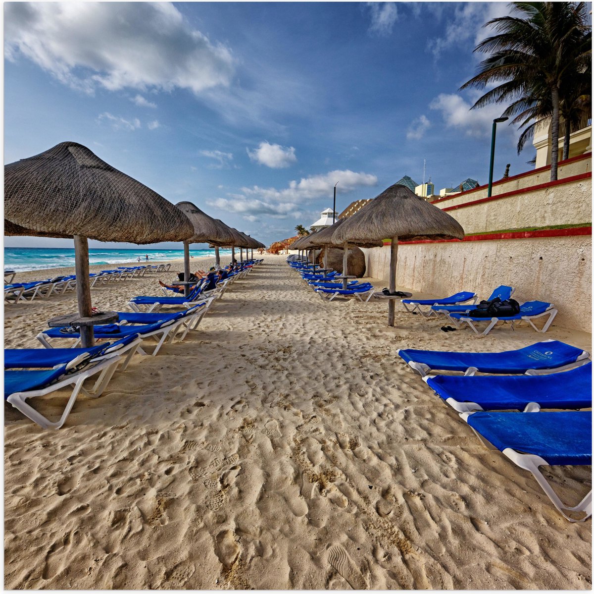 Poster Glanzend – Blauwe Ligbedden op Strand met Rieten Parasols - 80x80 cm Foto op Poster