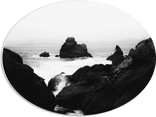 WallClassics - PVC Schuimplaat Ovaal - Golven tegen hoge Rotsen in het Water (Zwart- wit) - 56x42 cm Foto op Ovaal (Met Ophangsysteem)