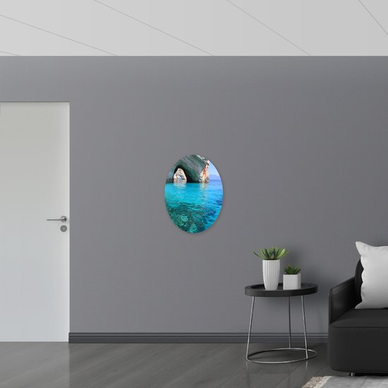 PVC Schuimplaat Ovaal - Grotten en Gesteente boven de Blauwe Zee - 51x68 cm Foto op Ovaal (Met Ophangsysteem)