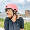Femme joyeuse aux cheveux blonds en queue, portant un casque rose avec logo "PRO SPORT LIGHTS".